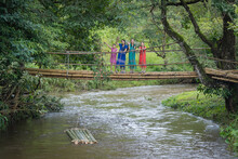 Teenagers And Young Girls Group Wearing Karen Dresses Are Walking Crosses On The Wooden Bamboo Bridge In The Countryside On The Mountain Of Doi Inthanon National Park At Chiang Mai, Thailand.