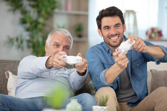 mature son and elderly father playing video game having fun