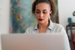 © Studio Marmellata - Soft focus of Middle Eastern female fashion designer in earbuds surfing internet on wireless computer and working remotely at desk