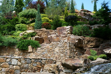 Canvas Print - View of coniferous green trees and a stone structure in the recreation park.