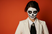 Scary Woman In Catrina Calavera Makeup And Festive Attire Looking At Camera On Red, Portrait