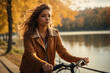 A young woman rides a bike by the lake on a sunny autumn day