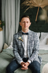 Wall Mural - Groom. Fashion men preparing for wedding. Handsome happy man on bed in bedroom or studio. Portrait of man. Groom is waiting for bride, first meeting. Luxury wedding day. Closeup.