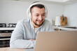 © Julija - Young man with laptop and headphones indoors at home, studying, freelance working
