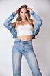 Charming young woman with blonde hairs and blue eyes. Female model wearing jeans top and trousers.