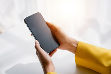 Wall Mural - close-up of a young woman holding a smartphone, typing a message, talking with friends. on social ne
