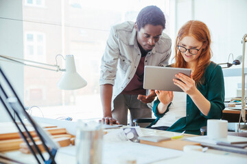 Young and diverse group of designers using a tablet in a modern business office