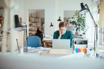 Young Caucasian male architect using the laptop and working on design in a startup company office