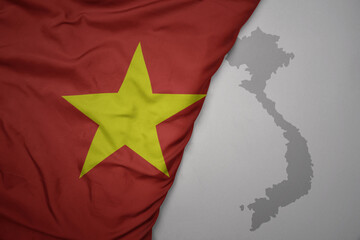 big waving national colorful flag and map of vietnam on the gray background.