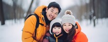 Chinese Family Of Young Parents And Baby Girl Spending Time Together During Winter Holidays In The Snow