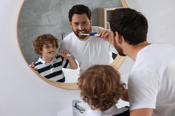 Wall Mural - Father and his son brushing teeth together near mirror in bathroom