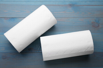 Rolls of paper towels on light blue wooden table, flat lay