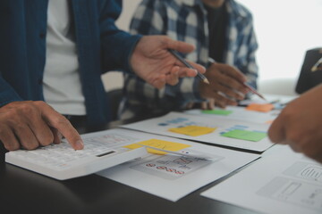 Close up ux developer and ui designer brainstorming about mobile app interface wireframe design on table with customer breif and color code at modern office.Creative digital development agency