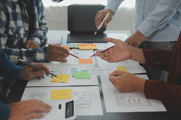 Close up ux developer and ui designer brainstorming about mobile app interface wireframe design on table with customer breif and color code at modern office.Creative digital development agency