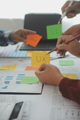 Close up ux developer and ui designer brainstorming about mobile app interface wireframe design on table with customer breif and color code at modern office.Creative digital development agency