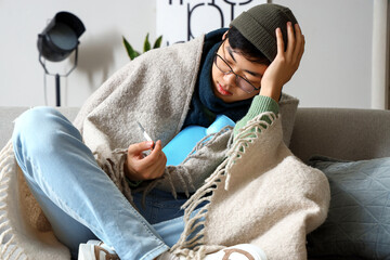 Canvas Print - Ill Asian man with hot water bottle at home