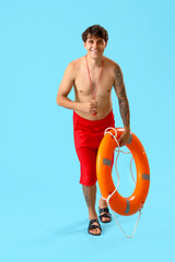 Canvas Print - Male lifeguard with ring buoy on blue background