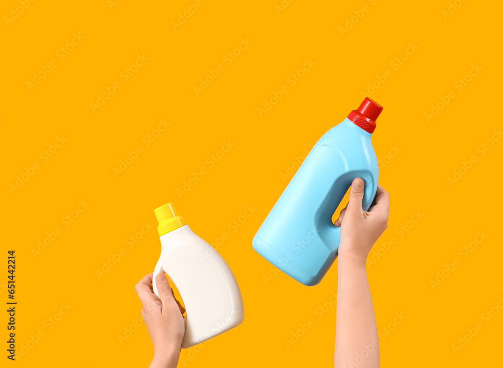 Woman with bottles of laundry detergent on orange background