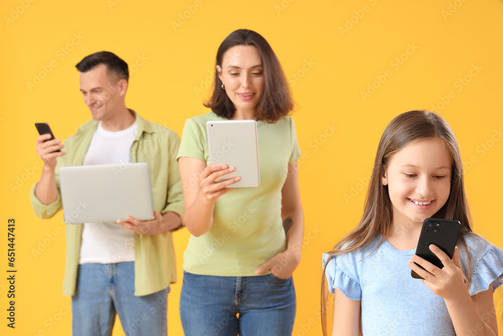 Happy family with modern gadgets on yellow background