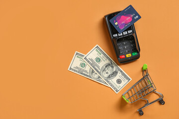 Poster - Shopping cart with payment terminal, credit card and dollar banknotes on beige background