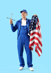 Wall Mural - Mature mechanic with cross wheel wrench and USA flag on blue background. Labor Day celebration