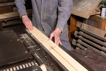 Wall Mural - A craftsman works on woodworking machines and saws in a furniture workshop