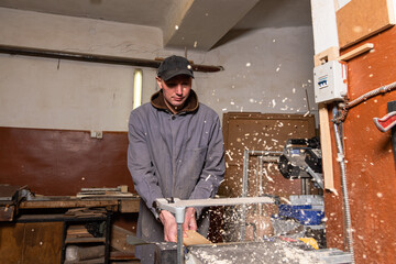 Wall Mural - A craftsman works on woodworking machines and saws in a furniture workshop