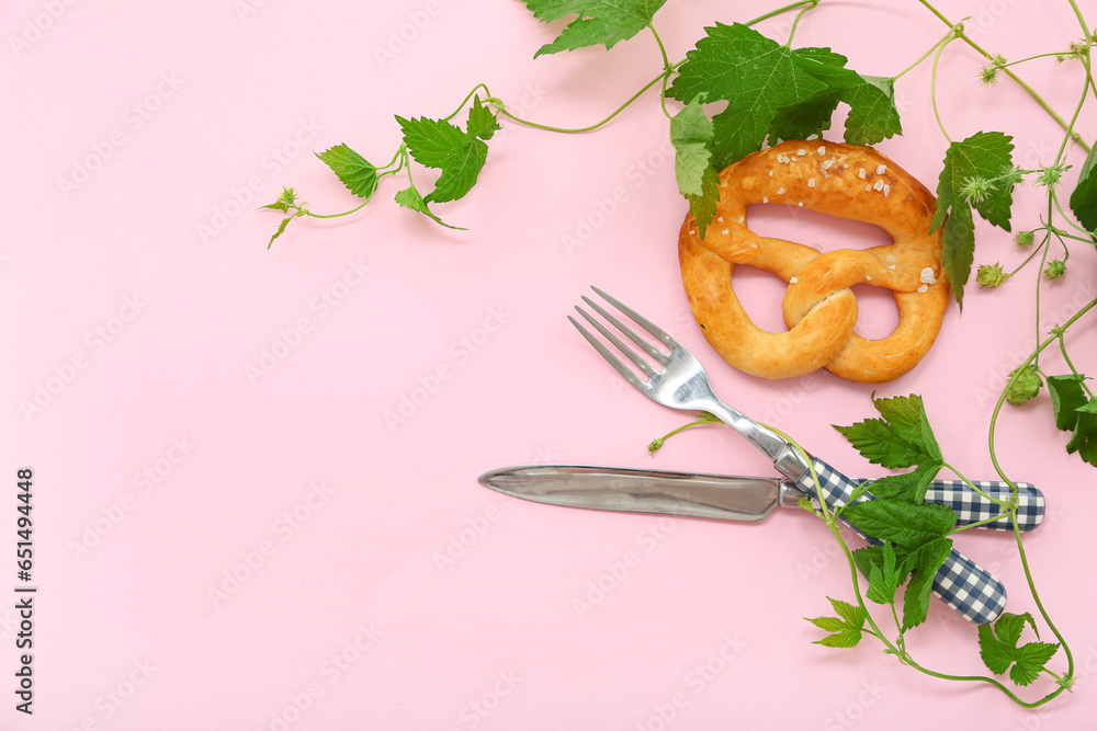 Soft pretzel with cutlery on pink background
