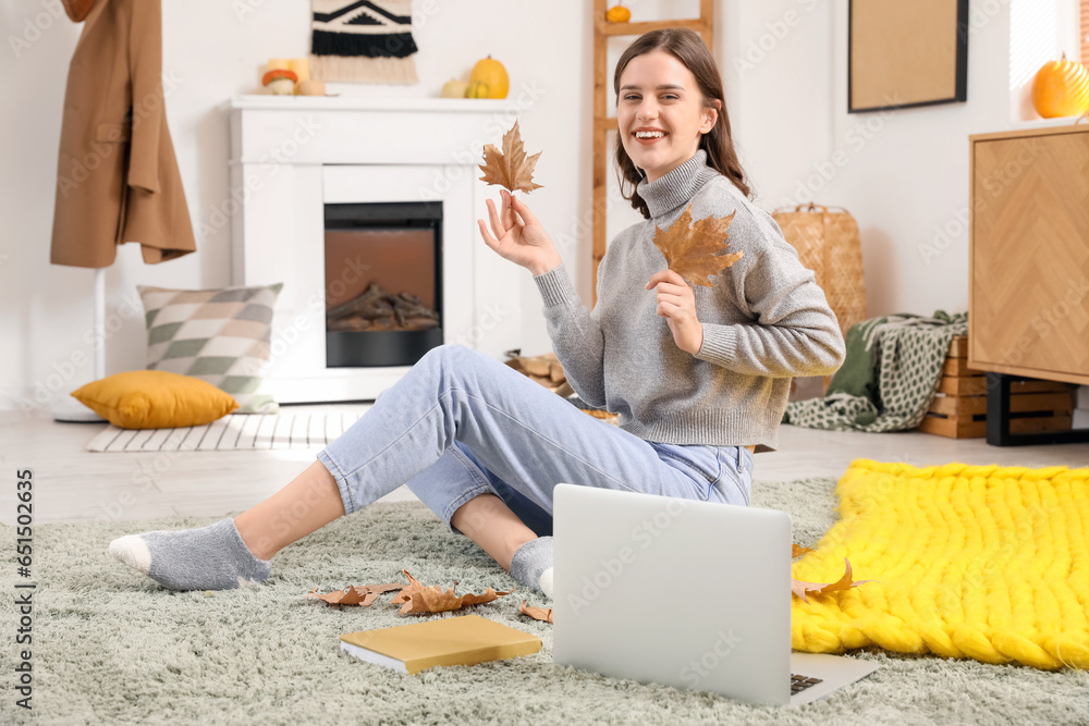 Young woman with autumn leaves at home