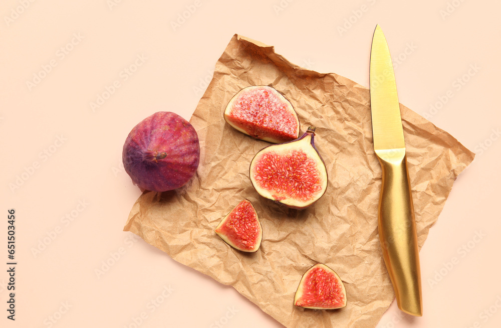 Fresh juicy cut figs with knife on pale pink background