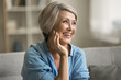 © fizkes - Happy beautiful blonde older mature lady touching facial skin, looking away with perfect toothy smile, laughing, enjoying elderly beauty care, thinking on good skincare result