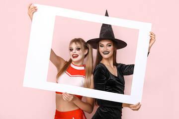 Female friends dressed for Halloween with frame on pink background