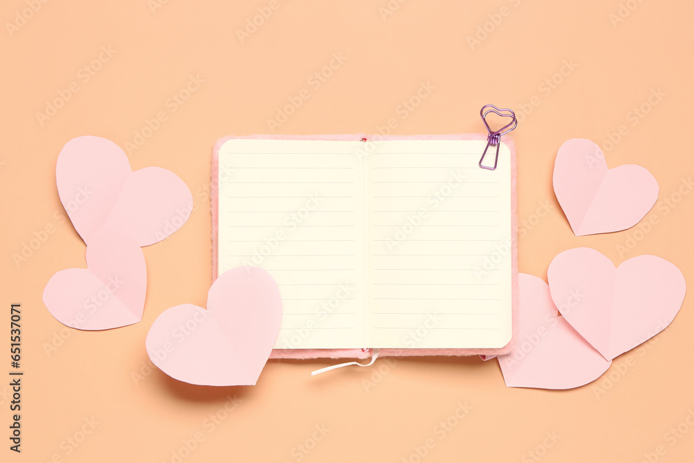 Beautiful paper hearts with open notebook on orange background. National Sweetest Day