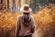 beautiful woman in sweater and hat walks in the autumn forest