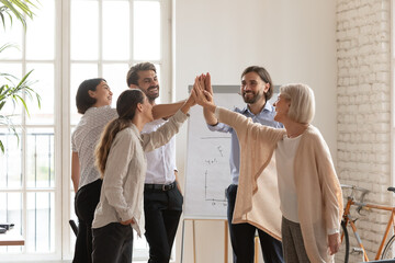 five diverse middle-aged 50s young mates celebrating common success standing in circle stack palms t