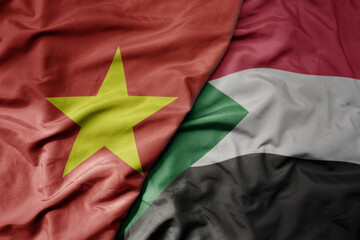 big waving realistic national colorful flag of vietnam and national flag of sudan .