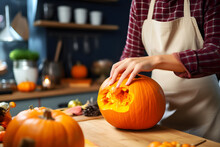Young Woman Making Halloween Pumpkin In The Kitchen