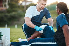 Sports, Injury And Man With Bandage For Accident, Emergency And First Aid For Muscle Sprain On Field. Fitness, Healthcare And Medic With Athlete With Knee Pain From Exercise, Workout And Training