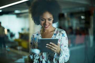 Wall Mural - Young African American woman using a tablet in a modern business office