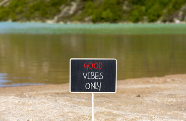 Wall Mural - Good vibes only symbol. Concept word Good vibes only on beautiful black chalk blackboard. Beautiful mountain lake sand beach background. Business motivational good vibes only concept. Copy space.