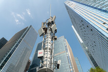 Low Angle View Of 5g Transmitter Tower And Modern Office Buildings.