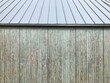Alte abgeblätterte Holzfassade mit neuem Blechdach mit Stehfalz