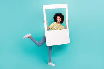 Wall Mural - Full length photo of cheerful optimistic girl wear trendy outfit have fun hold photography peek out hole isolated on cyan color background