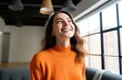 © Philipp - Joyful Woman in Modern Apartment: Professional, Beautiful, and Stylish in Orange Sweater