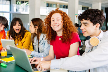 Wall Mural - Happy young group of diverse students studying together and working together with laptop at cafeteria in campus college. Smiling joyful female looking at camera. Education concept.