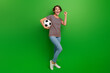 Leinwandbild Motiv Full size photo of delighted pretty girl hand hold football raise fist success luck isolated on green color background