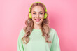 Portrait of optimistic young girl wear green jumper listen green wireless headphones sony brand advert isolated on pink color background