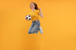 © New Africa - Emotional sports fan with ball jumping on yellow background
