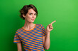 Leinwandbild Motiv Photo portrait of attractive young woman finger pointing empty space wear trendy striped clothes isolated on green color background