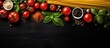 Top view image of Italian pasta ingredients on black table including spaghetti tomato basil and garlic with copy space